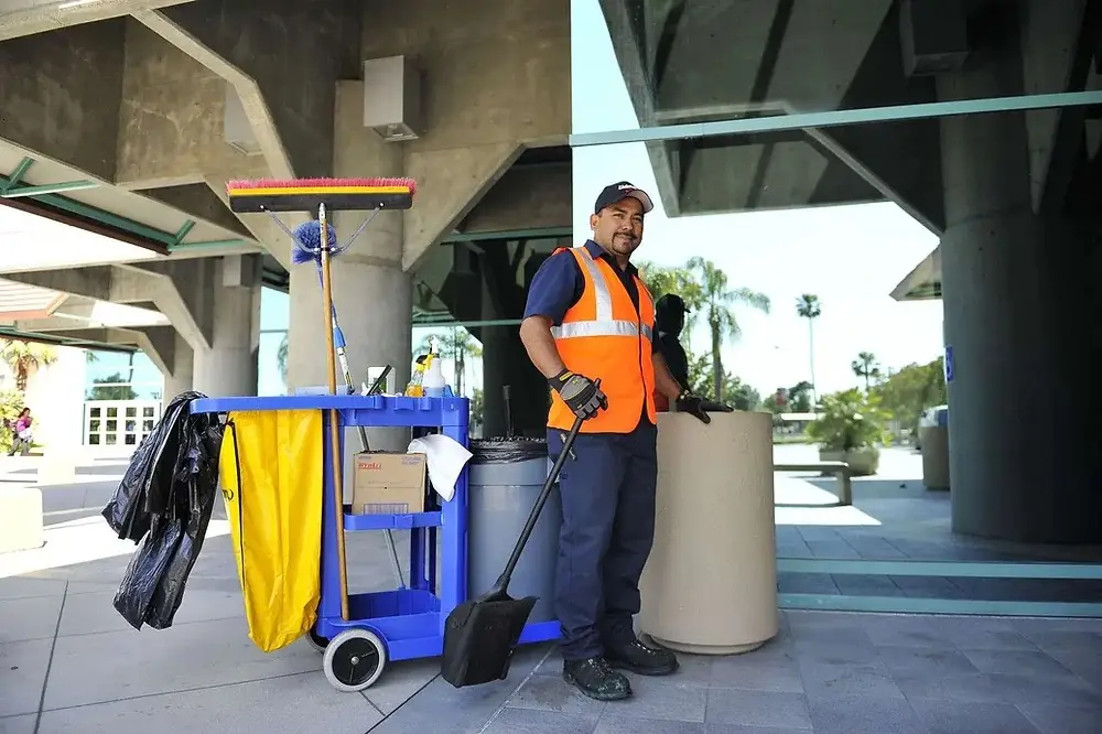 Day porter with a cleaning cart at the entrance of a commercial building